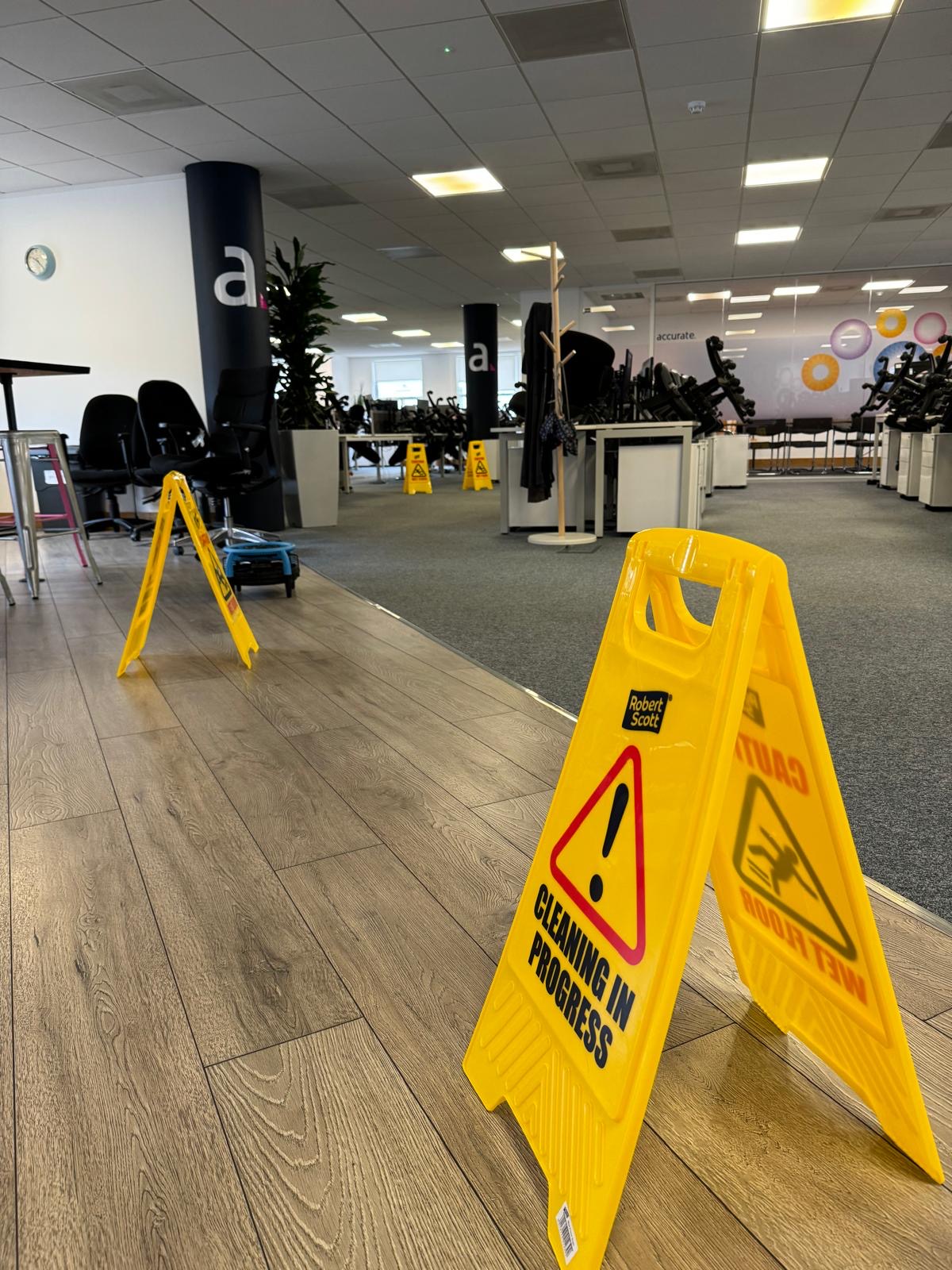 Commercial office floor being cleaned, with Cleaning in Progress and Wet Floor signs in place to keep the workplace safe.